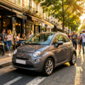 Une Fiat 500 grise stationne devant un bâtiment moderne, mettant en valeur son design élégant et sa couleur neutre.