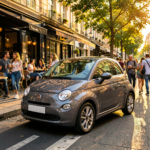 Une Fiat 500 grise stationne devant un bâtiment moderne, mettant en valeur son design élégant et sa couleur neutre.